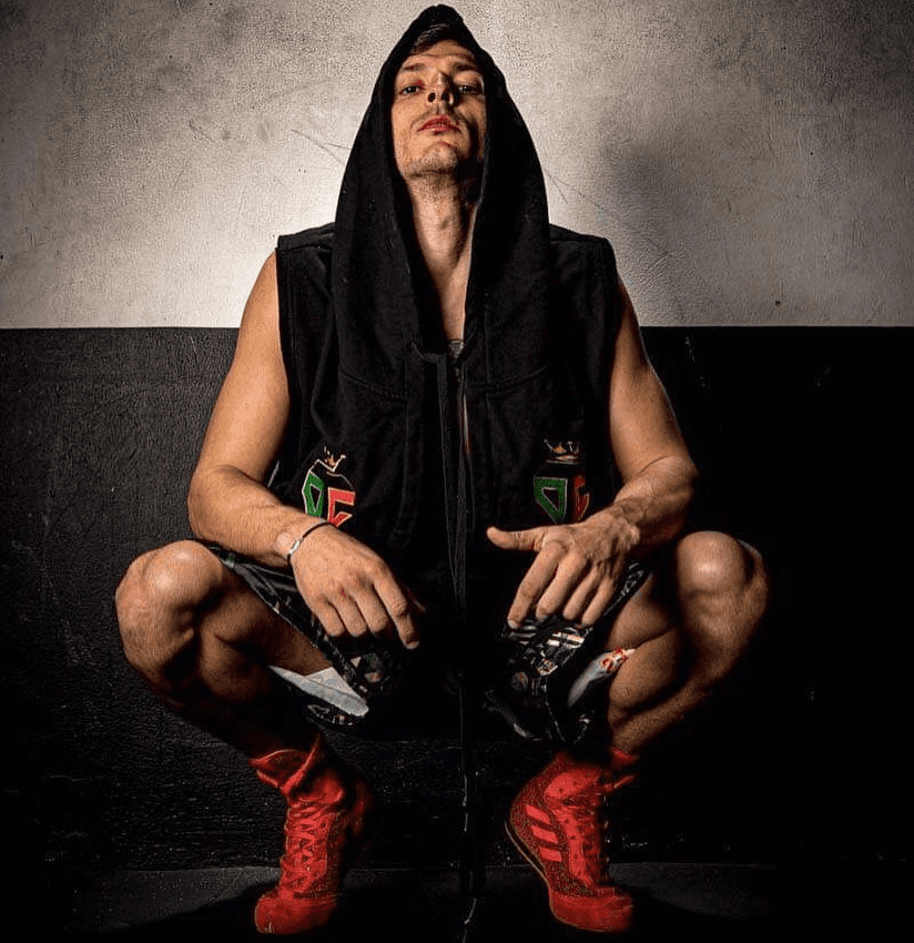 Danilo Dash Creati sitting in a dark gym, hood up, preparing mentally before a fight.