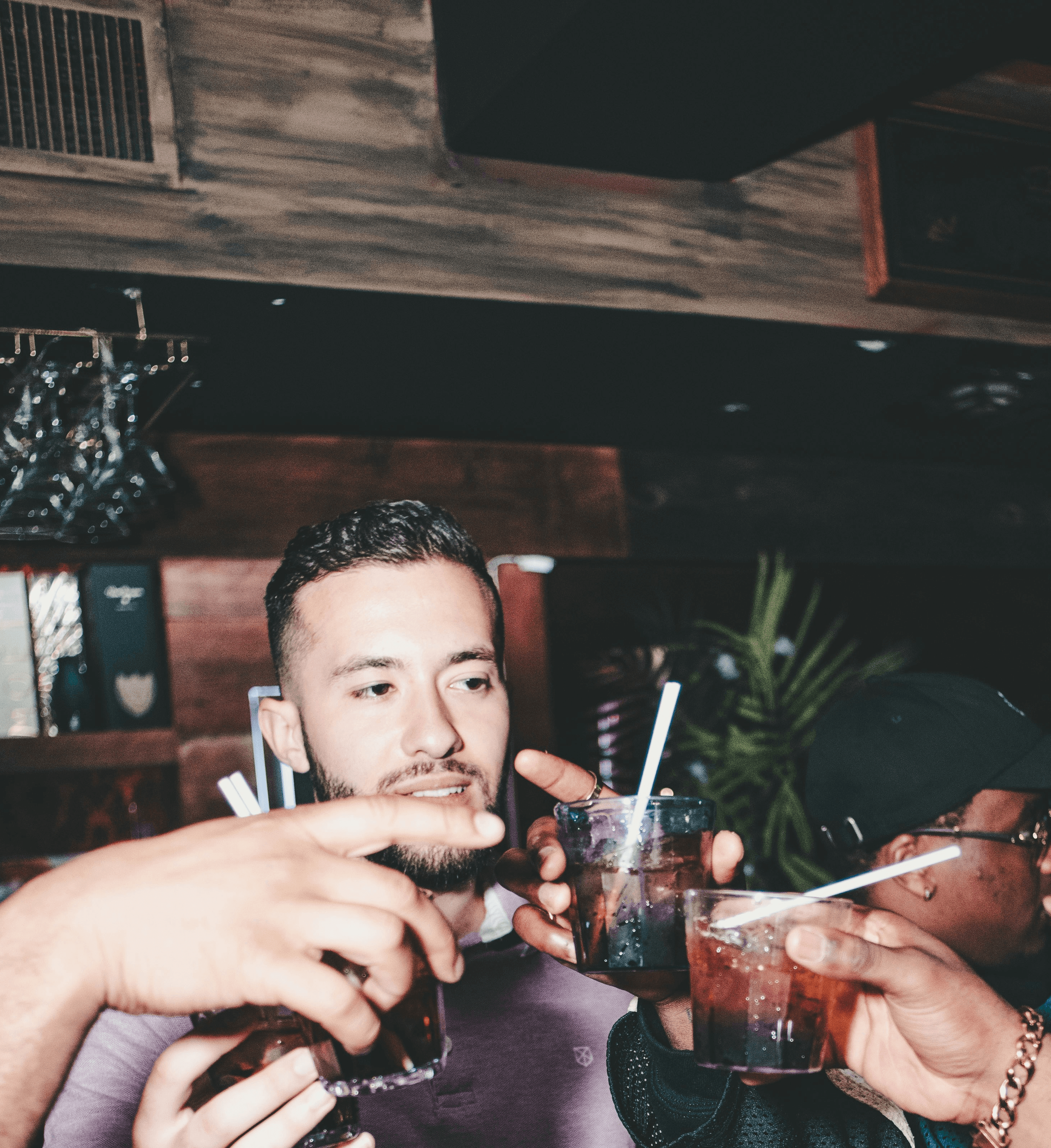 three people holding glass bottles while talking