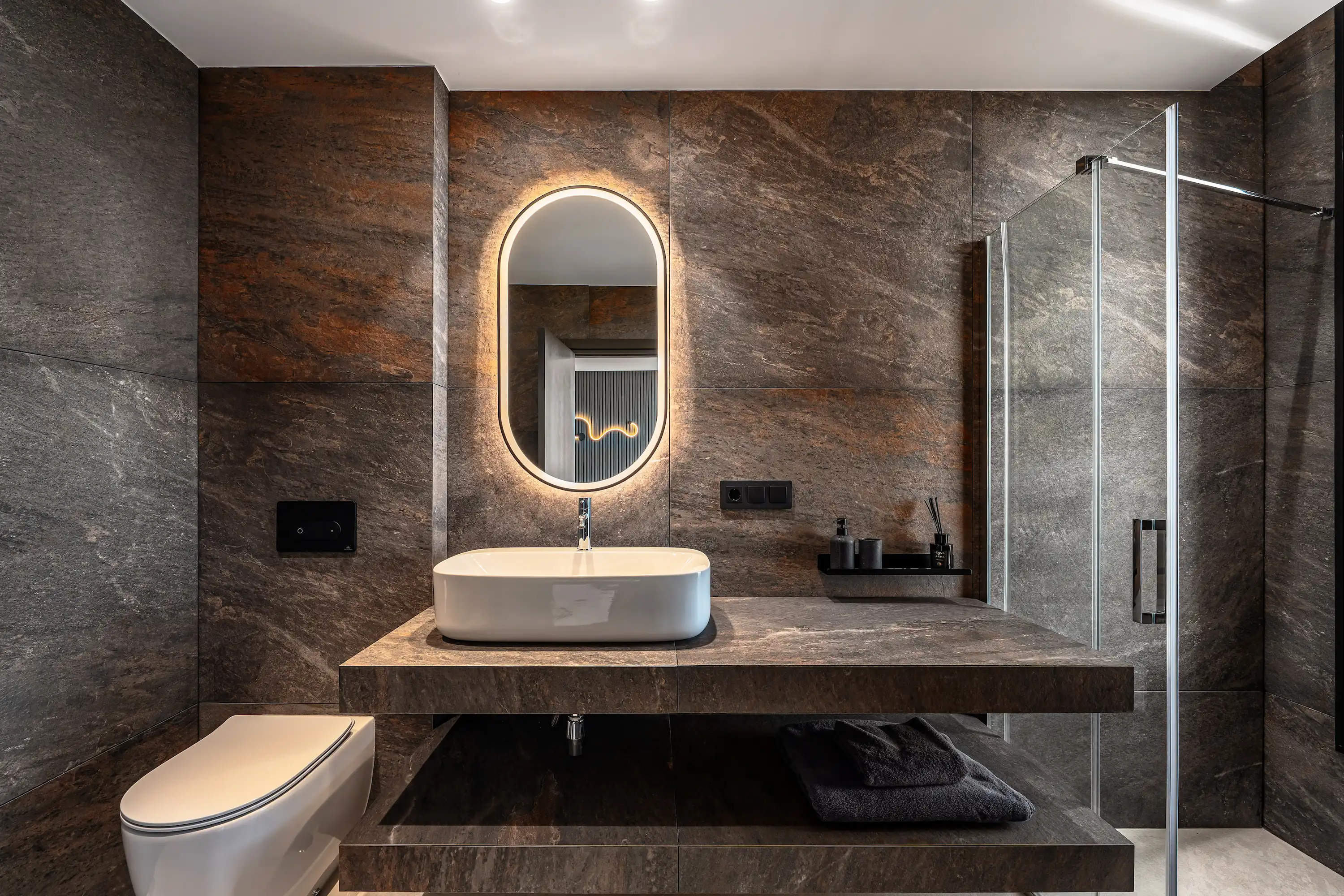 Villa Vista Marbella bathroom with stone-clad walls, floating vanity, and illuminated oval mirror