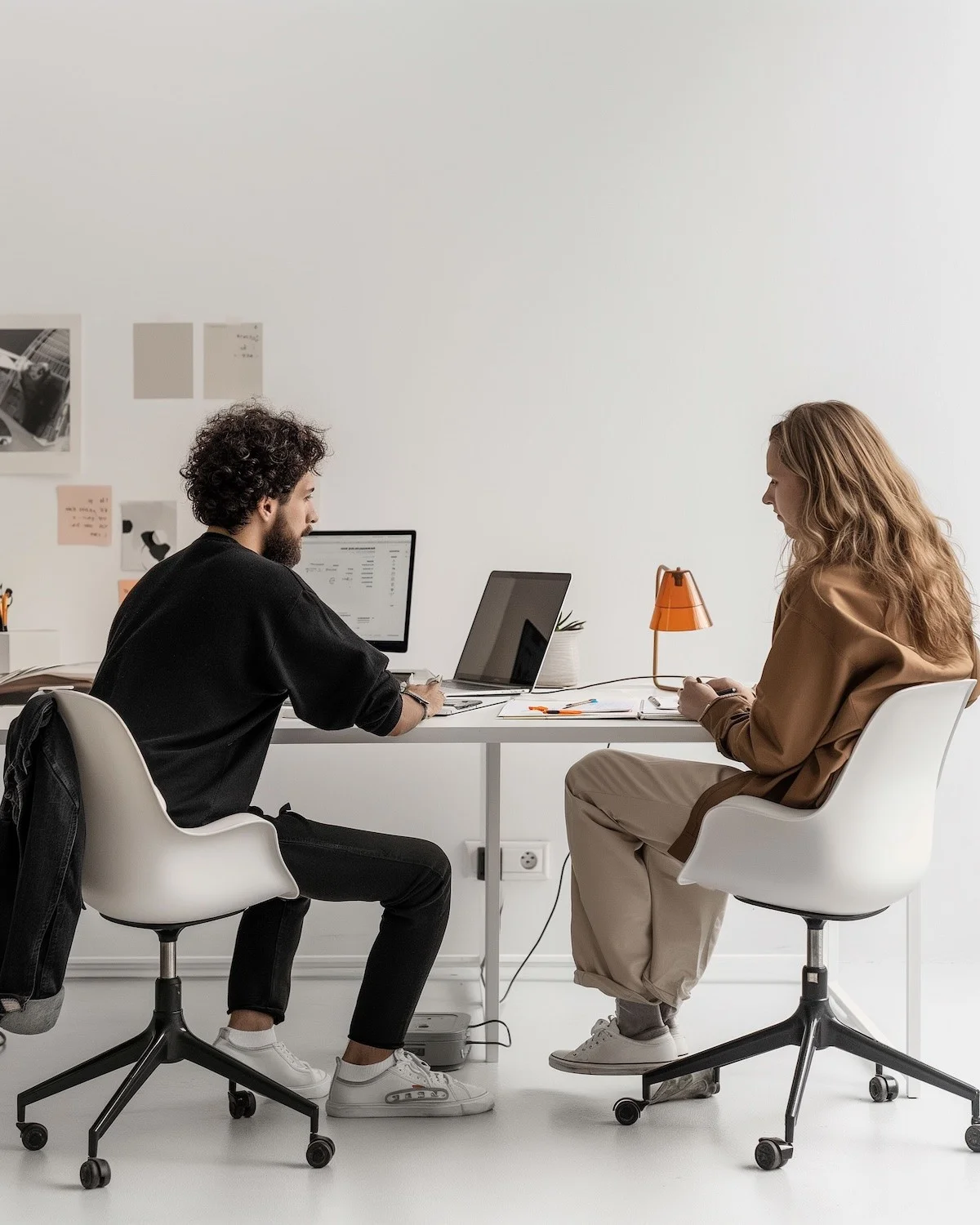 Group of people gathered around a wooden table with laptops, shaking hands during a team meeting.