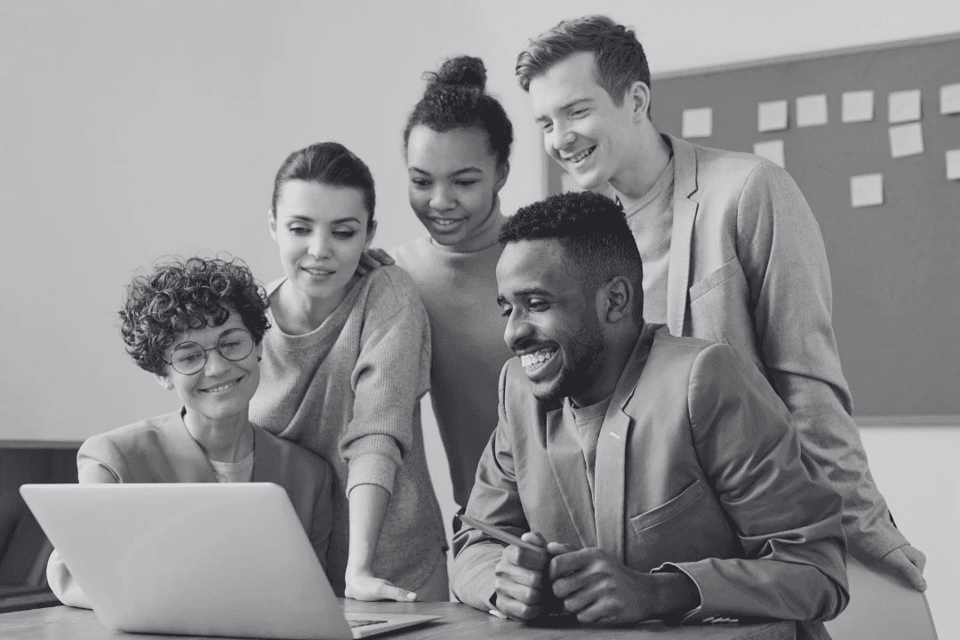 Equipo diverso colaborando frente a una computadora en un entorno laboral inclusivo