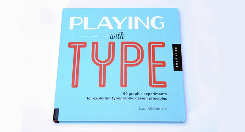 A photo of a cyan notebook with some white and red text that says: Playing with Type.