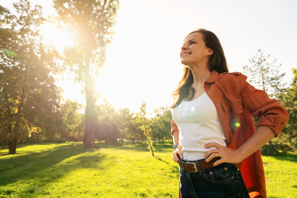 A woman standing outside with hands on hips trying to manage stress