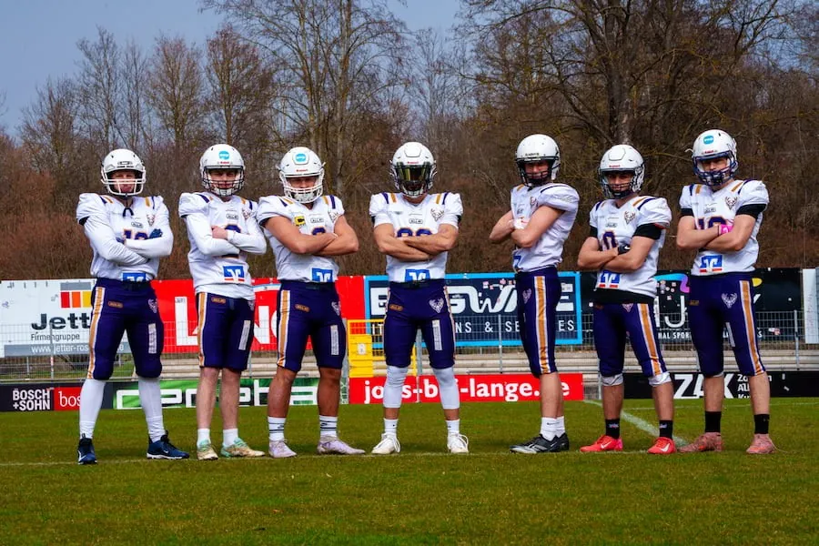 Sieben Spieler der Bucks in weißen Trikots stehen mit verschränkten Armen nebeneinander auf dem Spielfeld.