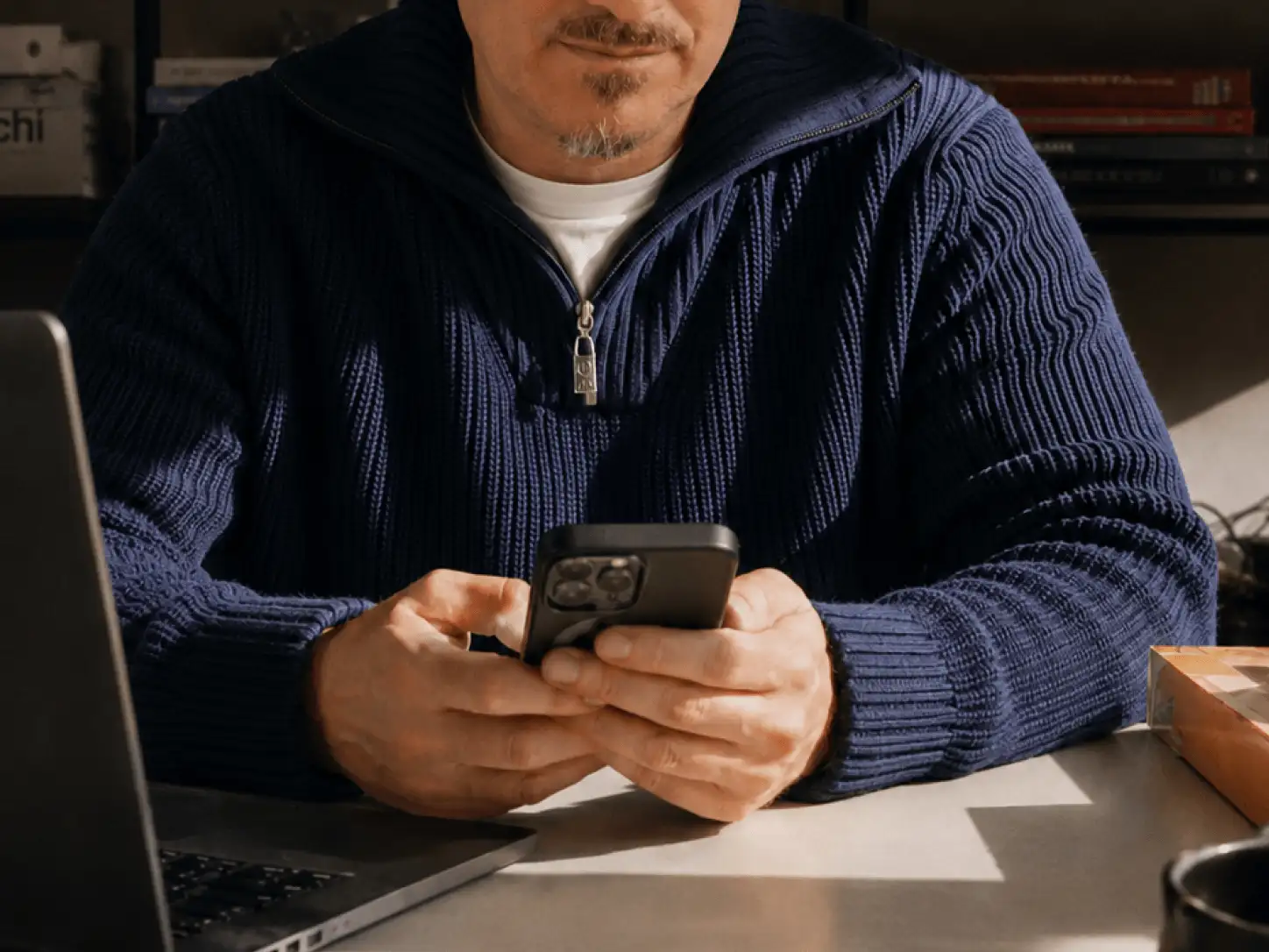 Mann am Schreibtisch mit Handy in der Hand