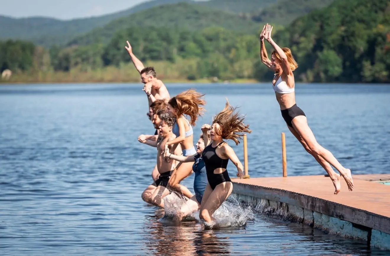 Guests jumping off the dock into the lake at Camp Lenox