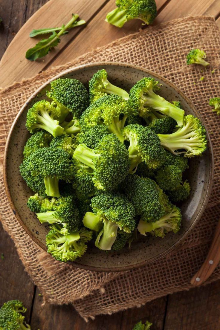 Fresh green broccoli florets served in a rustic ceramic bowl, placed on a wooden table with burlap cloth underneath for a farm-to-table aesthetic