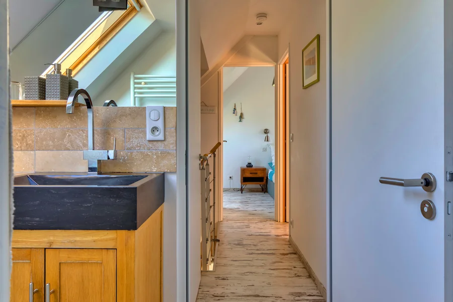Salle de bain luxueuse et couloir menant à la chambre sous combles du cottage Étretat à la Villa Argonne en Normandie.