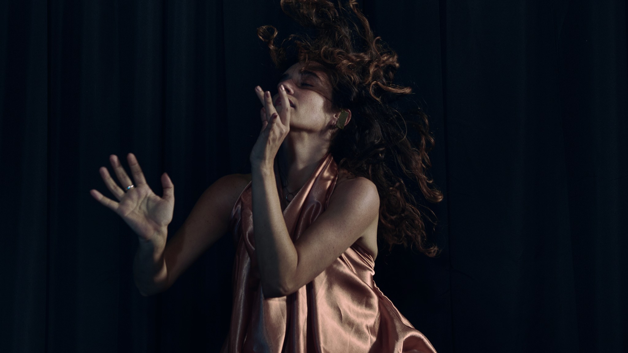Dancer captured mid performance with artistic and expressive movements against a dark background.