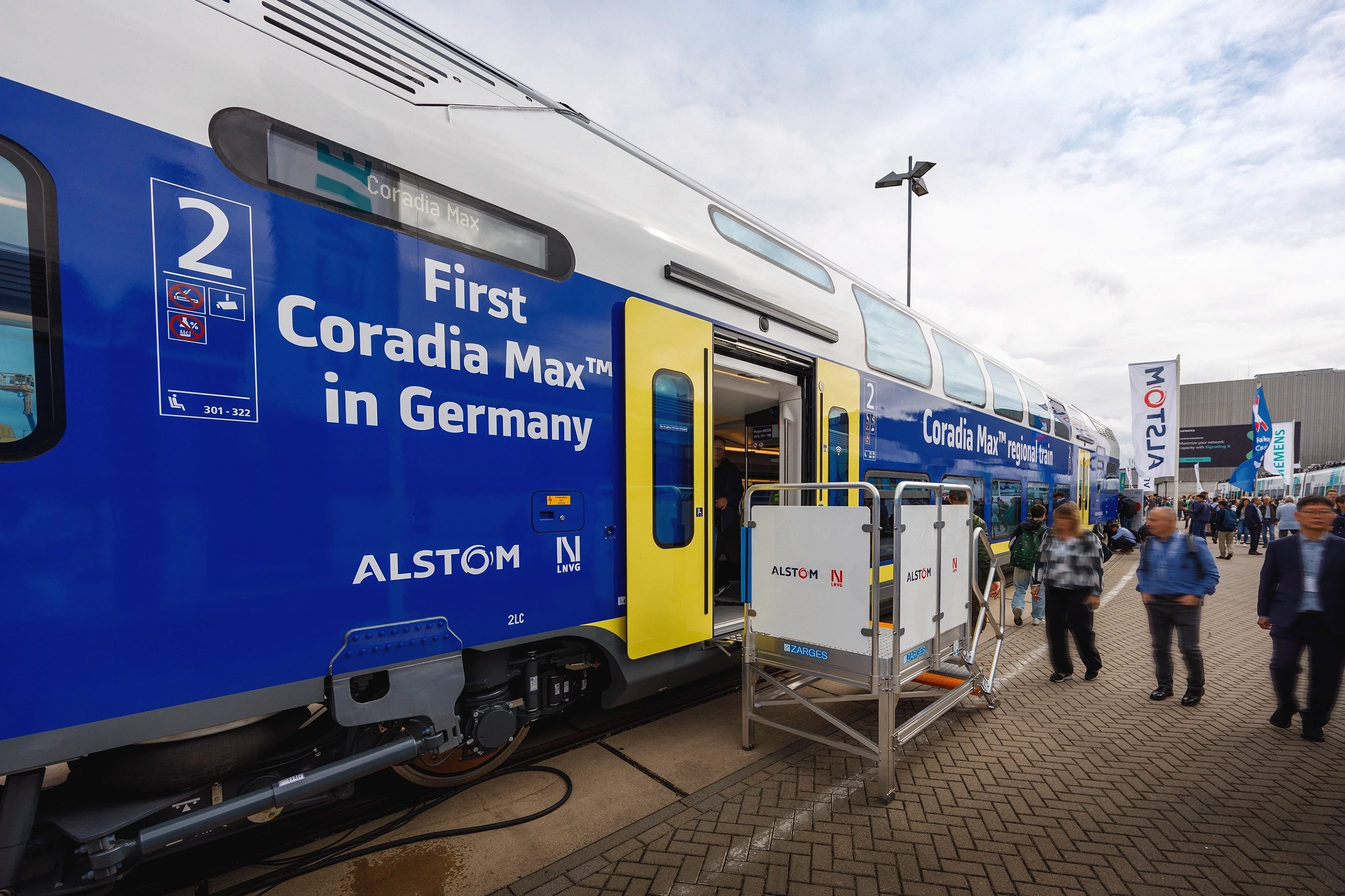 Alstom Coradia Max Doppelstockzug auf der InnoTrans 2024: blau-weißer Regionalzug mit Aufschrift ‚First Coradia Max in Germany' und Alstom-LNVG-Logo