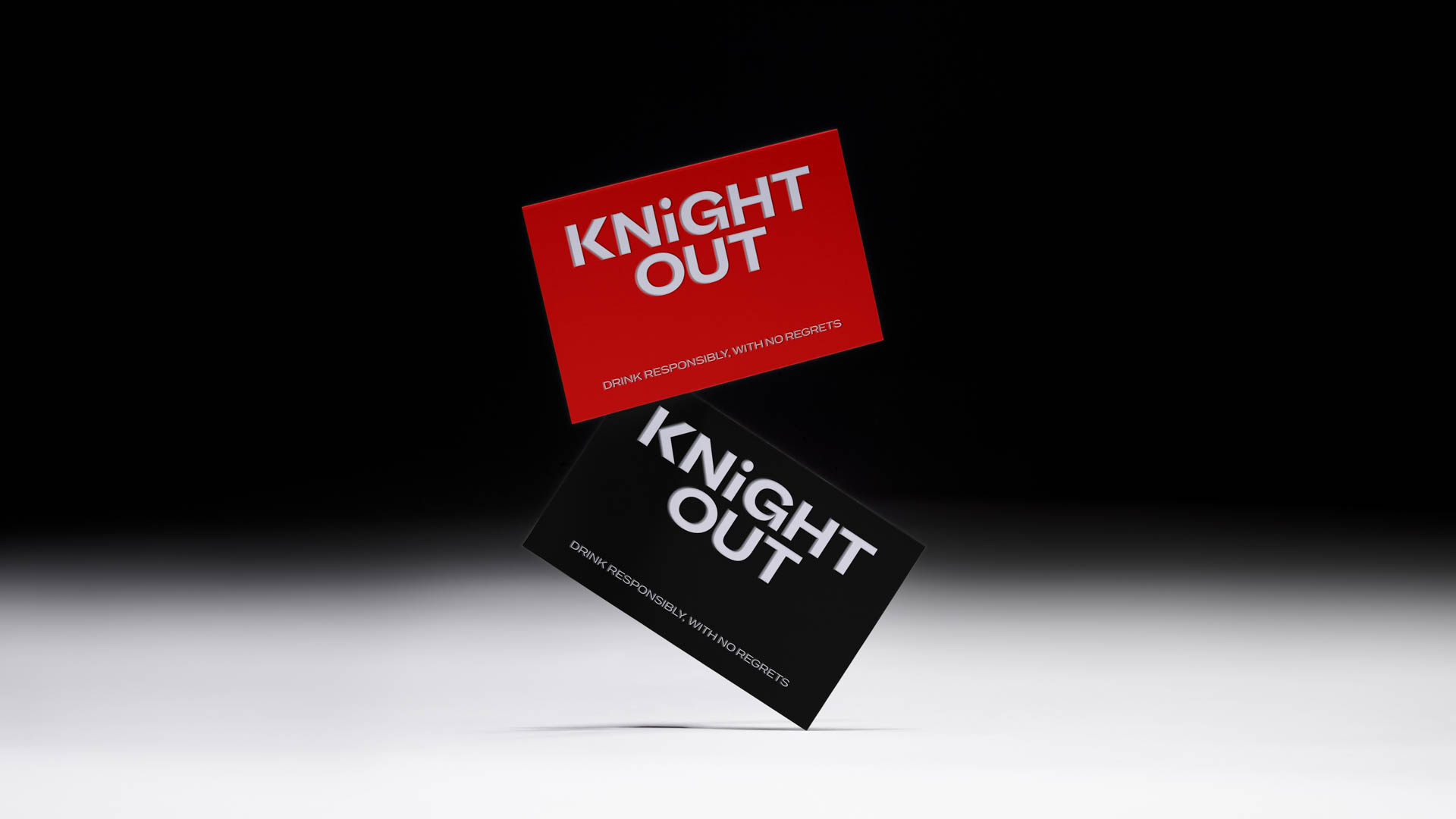 Two business cards are shown against a black background. The top card is red and displays the text "KNIGHT OUT" in white. Below it, a black card is angled and features the same text in white. Both cards include the phrase "DRINK RESPONSIBLY, WITH NO REGRETS" in smaller text at the bottom.