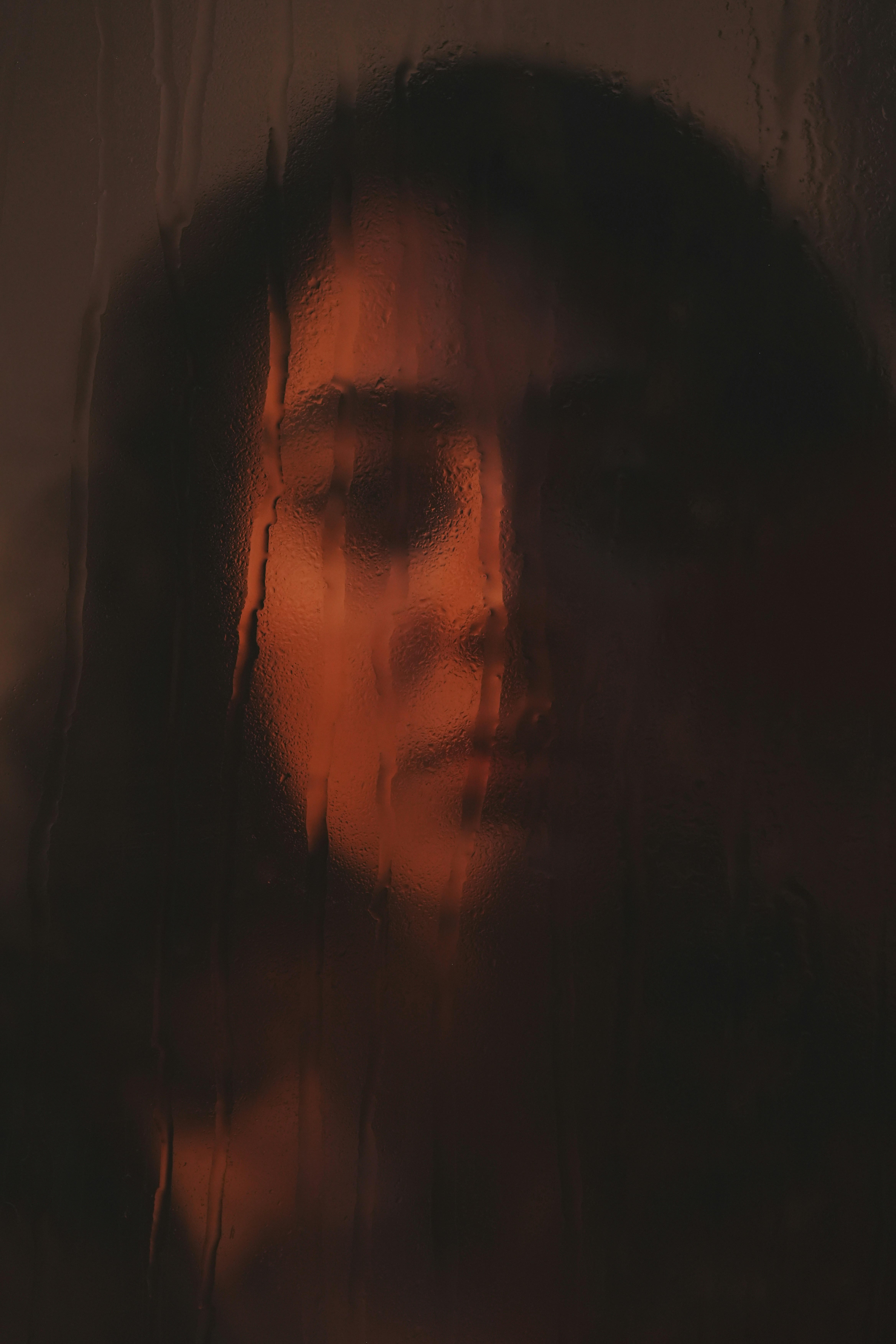 Woman's face seen through rain-streaked glass