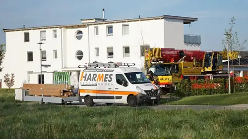 Firmenfahrzeug von Harmes Bedachungen mit Kran auf einer Baustelle