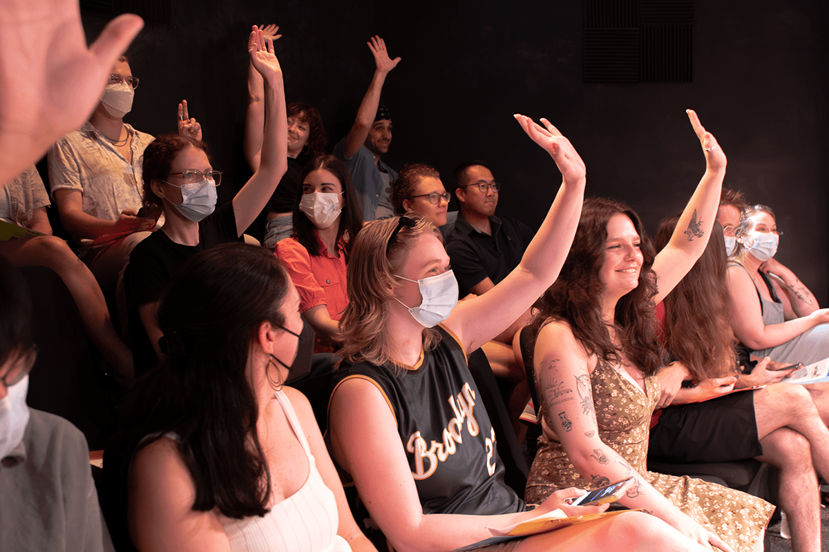 Audience members raise their hands to vote.