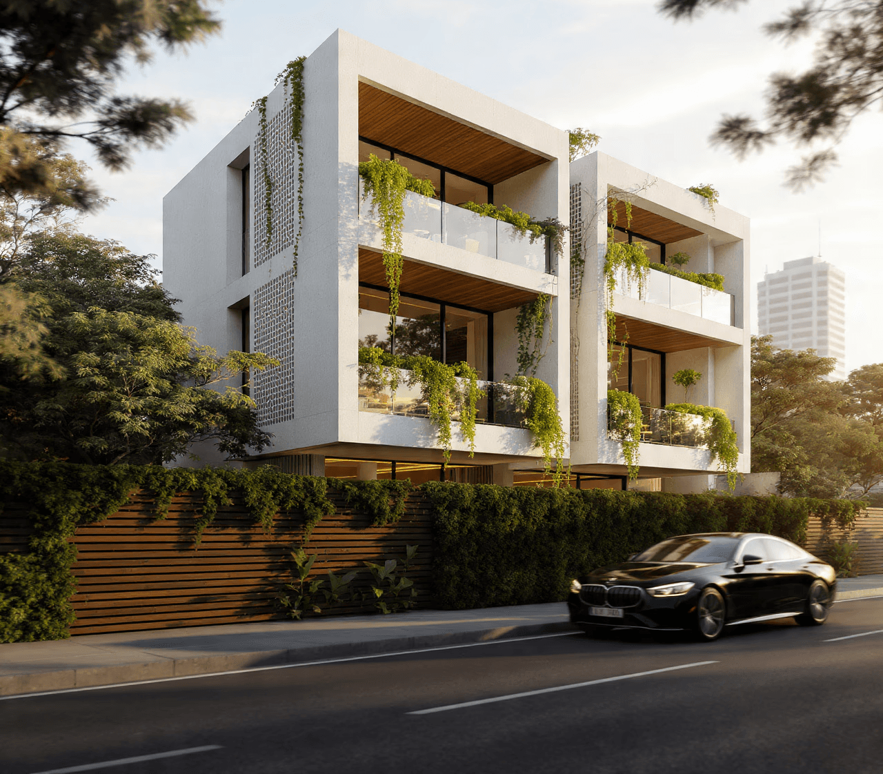Modern white three-story building with lush greenery on balconies, set against a clear sky. A sleek black car drives by on a tree-lined street.