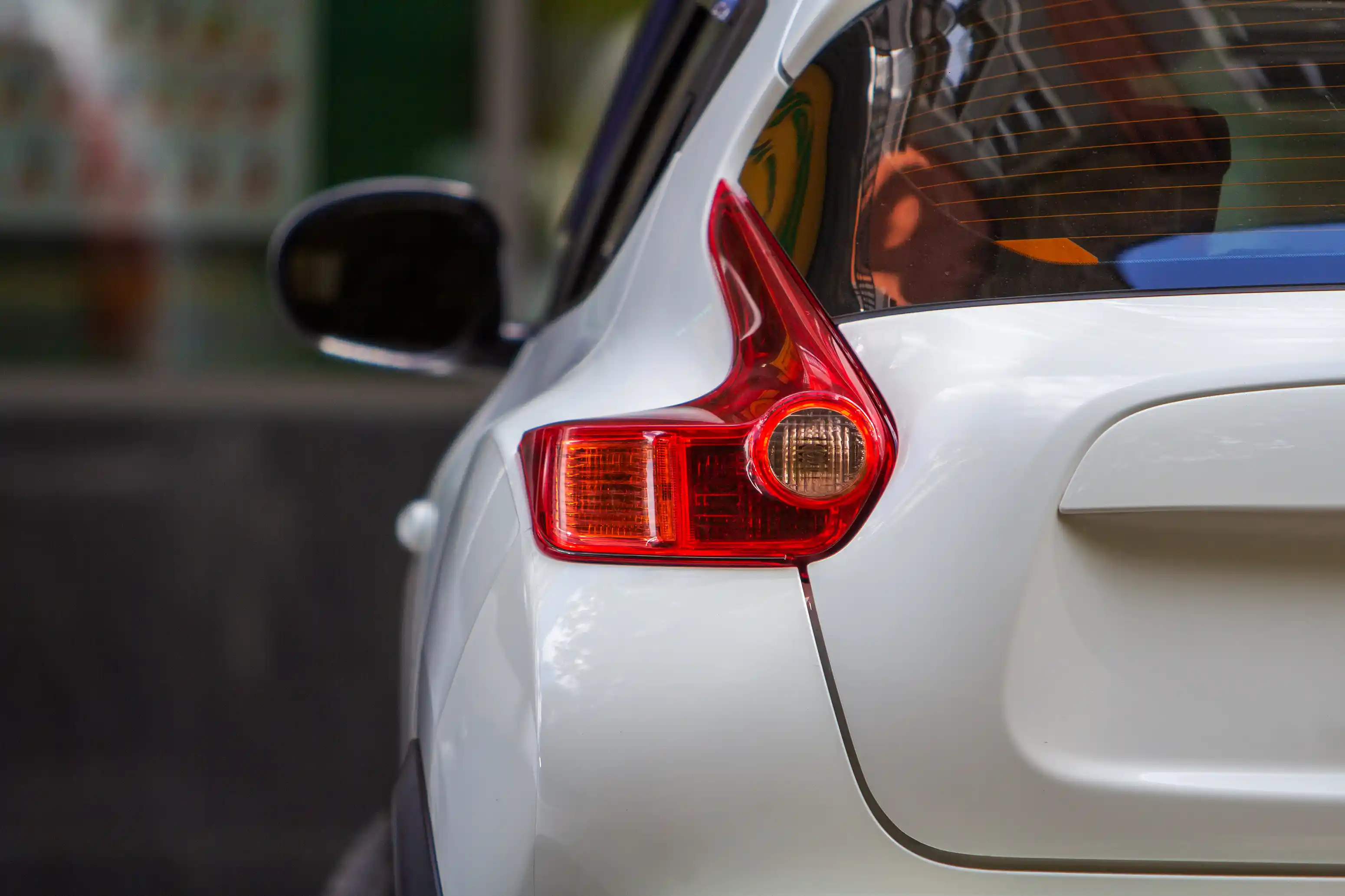Close-up of the rear tail light and bumper of a white car
