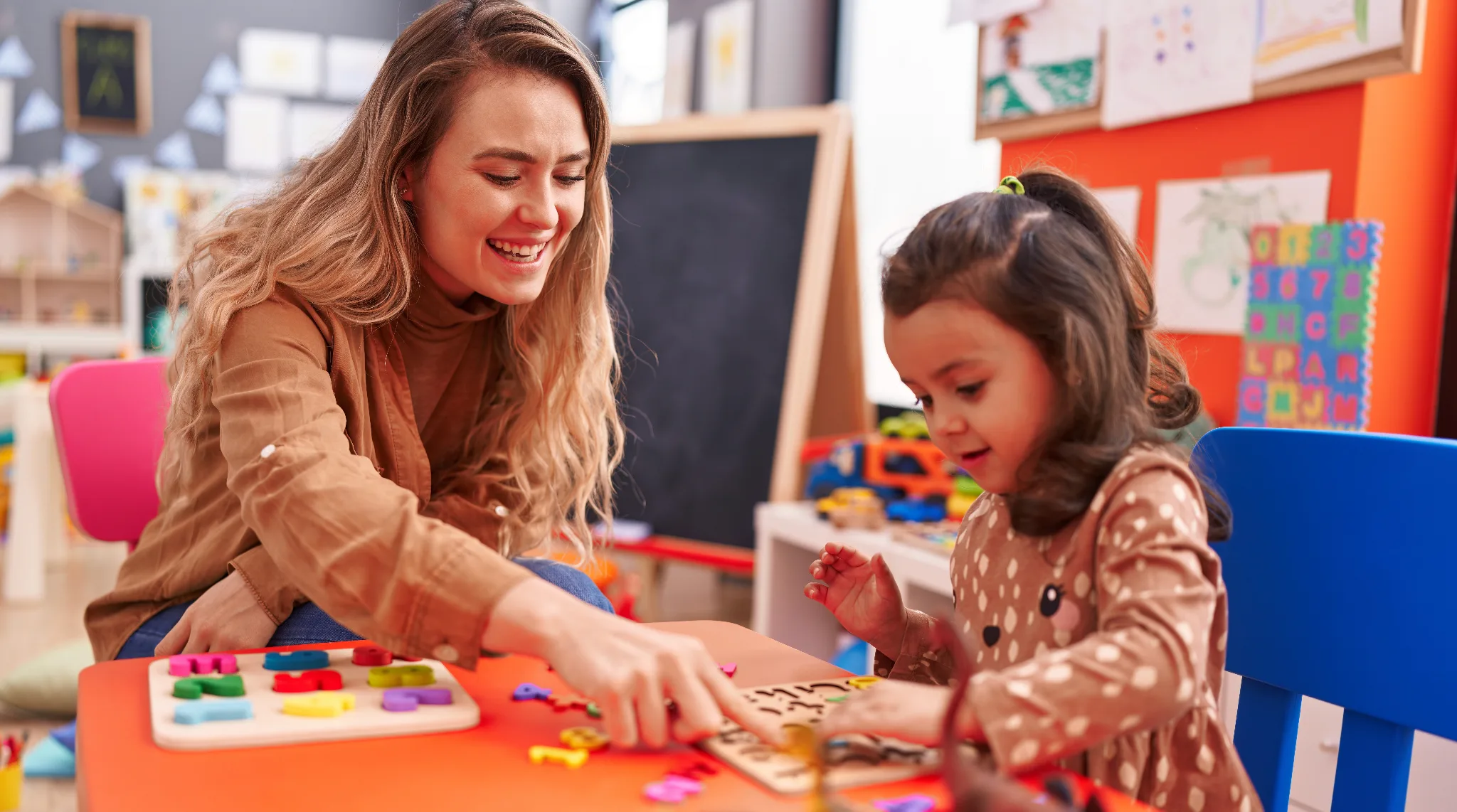 Couselor sitting at table with young girl doing activities