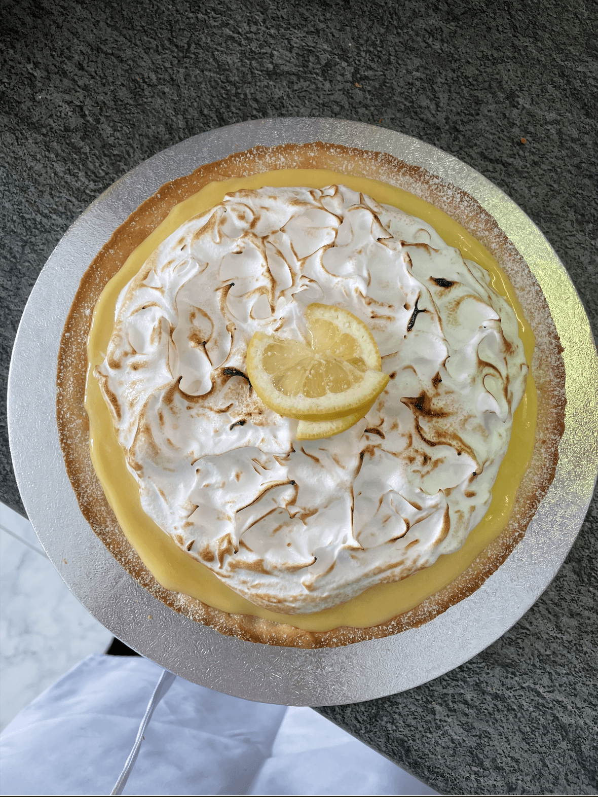 Overhead view of a lemon meringue tart topped with a lemon slice.