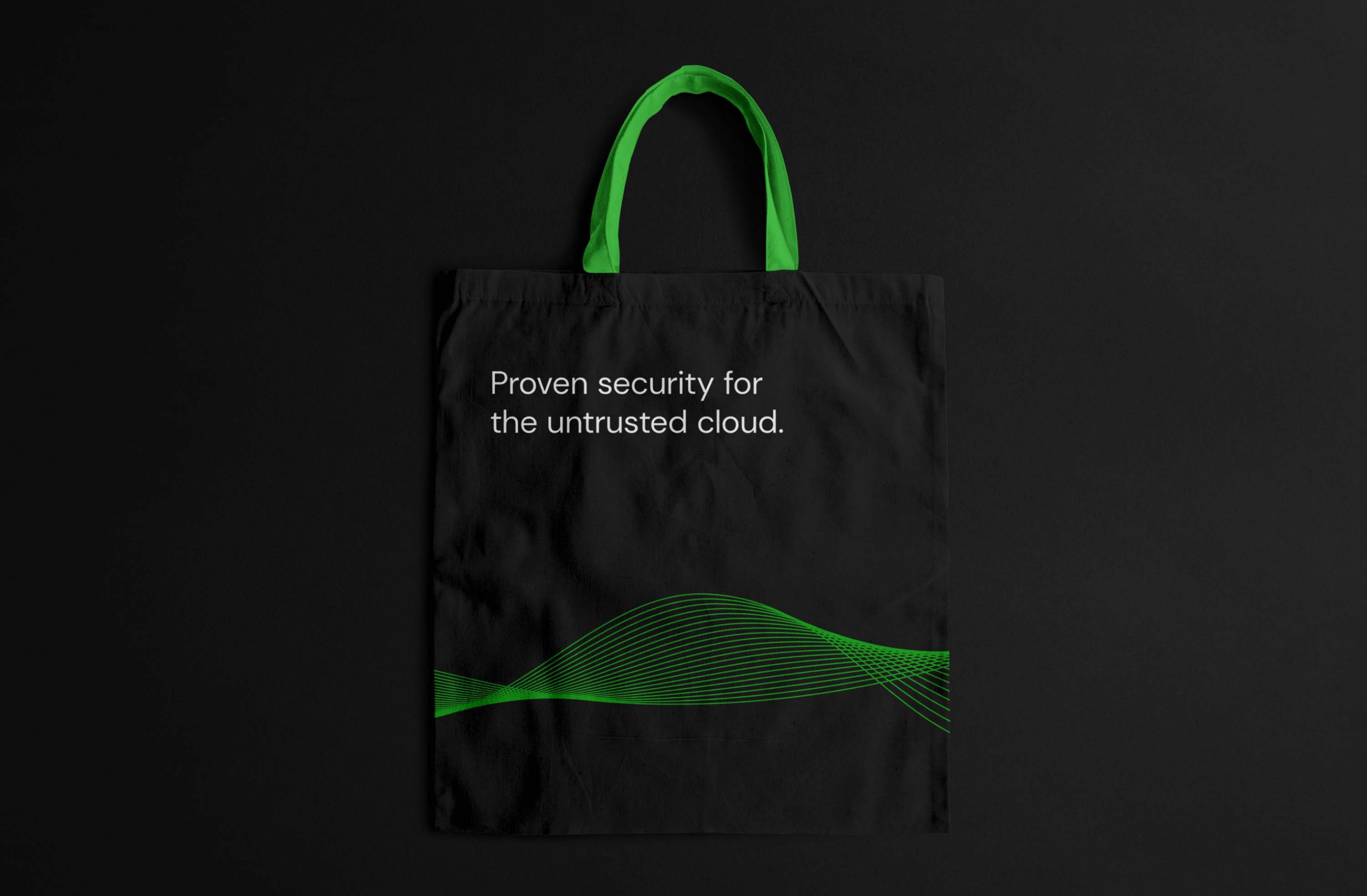 Black reusable tote bag featuring a green wave design and the text 'Proven security for the untrusted cloud.' for eco-conscious branding.