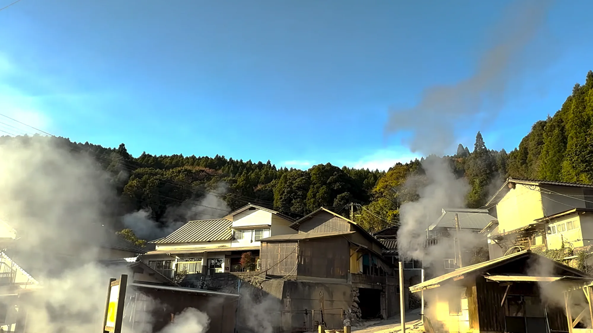 Dense steam venting behind rooftops near Kurokawa