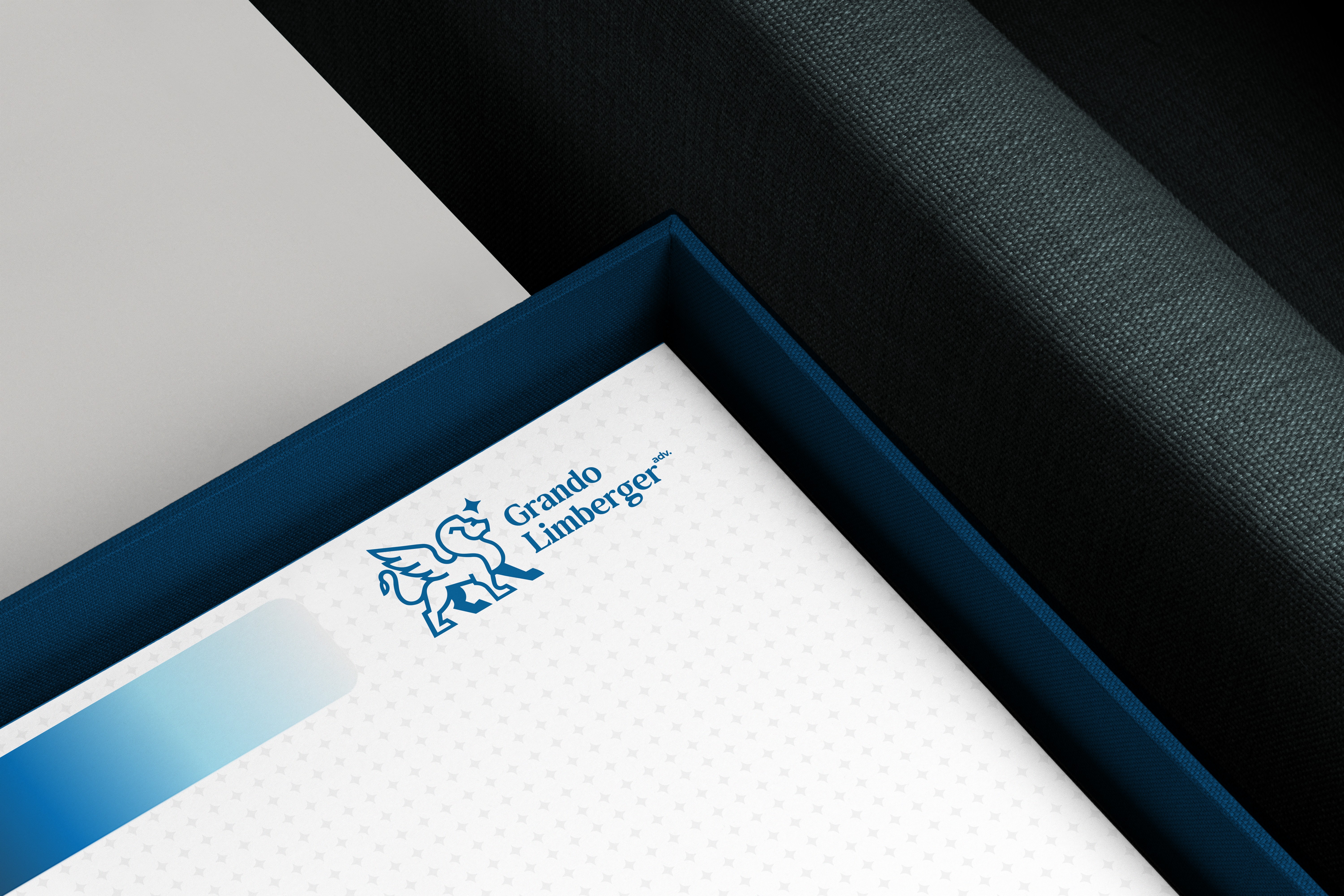 Caderno branco com o logotipo Grando Limberger em uma caixa azul, ilustrando a identidade visual e organização do escritório.