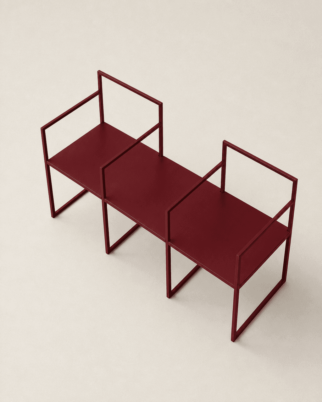 Burgundy red metal two-seater waiting bench featuring square-frame arms and open rectangular backrests against a neutral background.