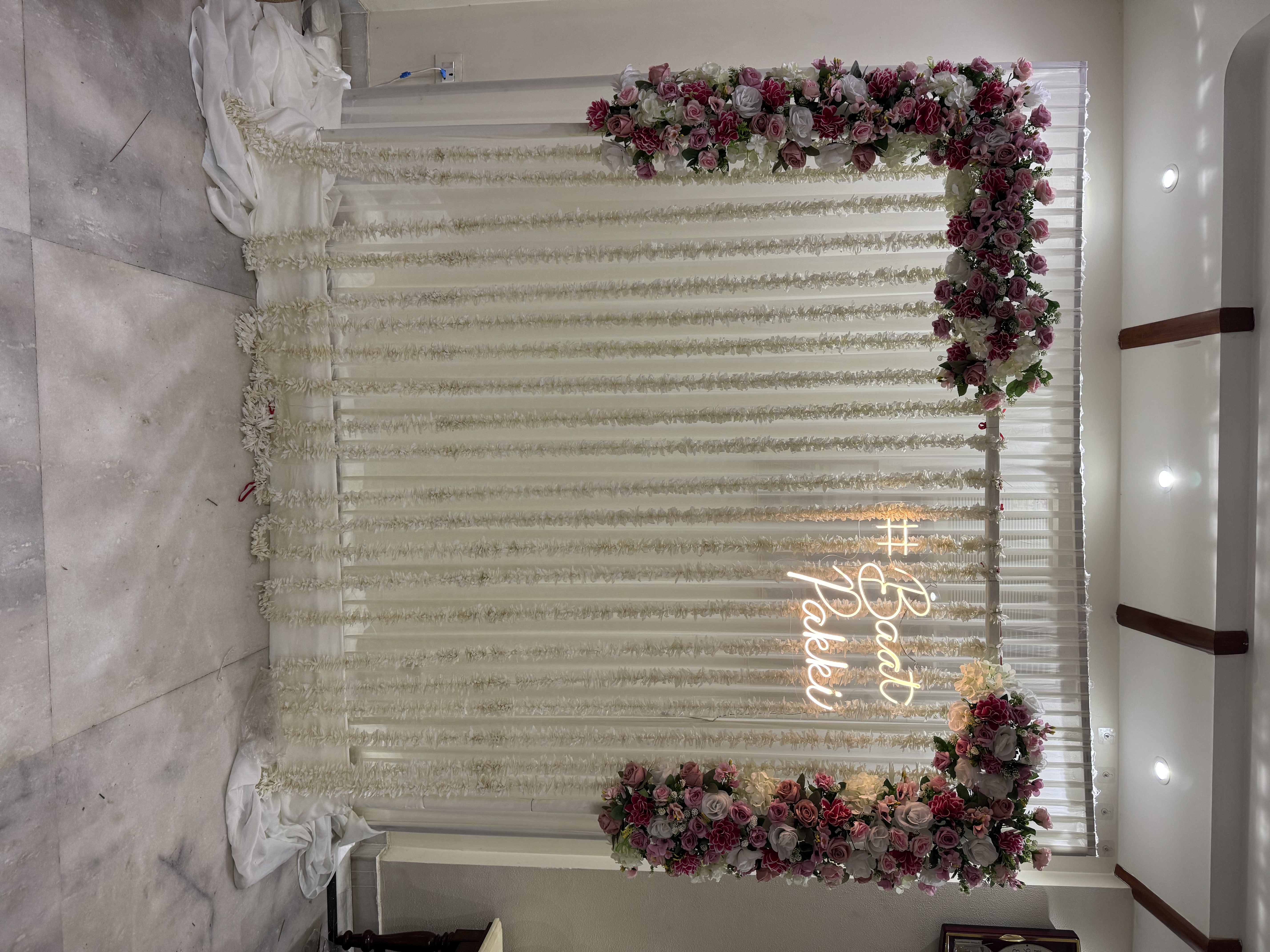 Engagement or roka backdrop with Baat Pakki neon sign, pink & rose gold flowers for home decoration in Janakpuri & Pitampura