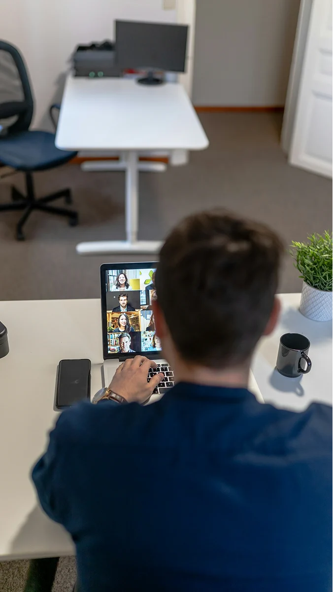 A man attending a video call on his laptop at home.