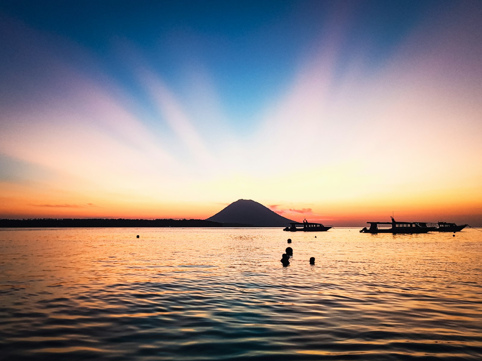 Sunset behind the volcanic cone of Manado Tua seen from the water