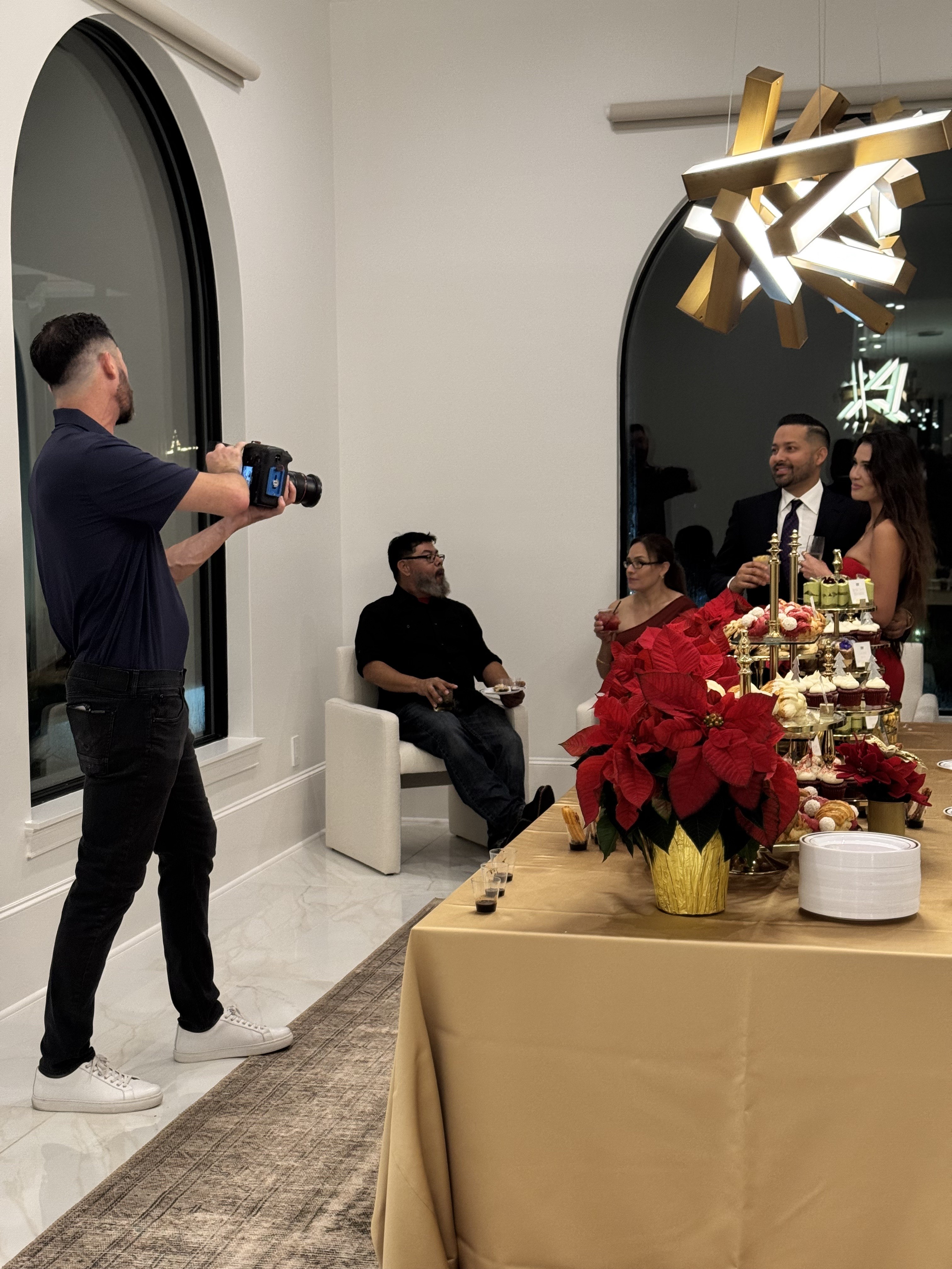 Photographer capturing guests beside a dessert table at a celebration.