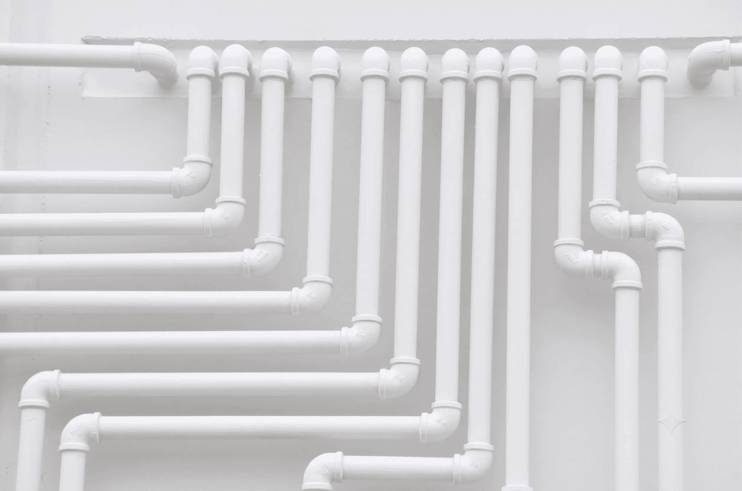 An array of white supply pipes running across a wall