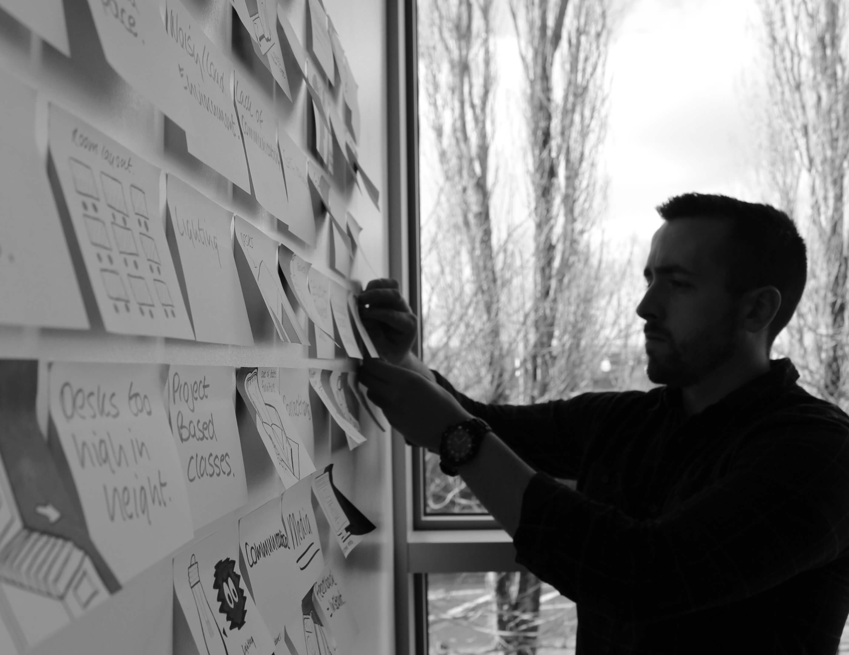 Side facing shot of cormac placing post-it on wall