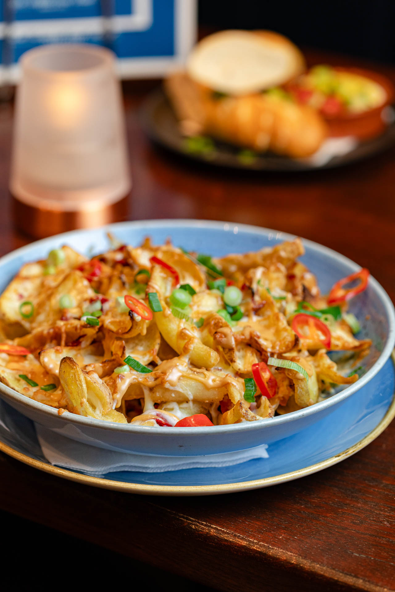 Een tafel met een kaars en een schaal vol verse gemaakte nacho's