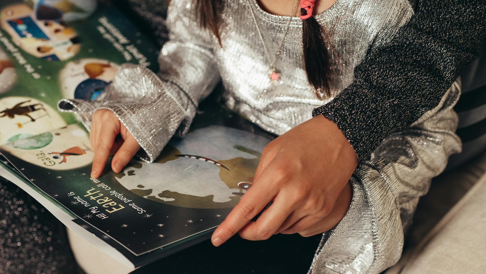 Close-up of a teacher's hands organizing tactile materials like sand, shells, and letters for play and learning.
