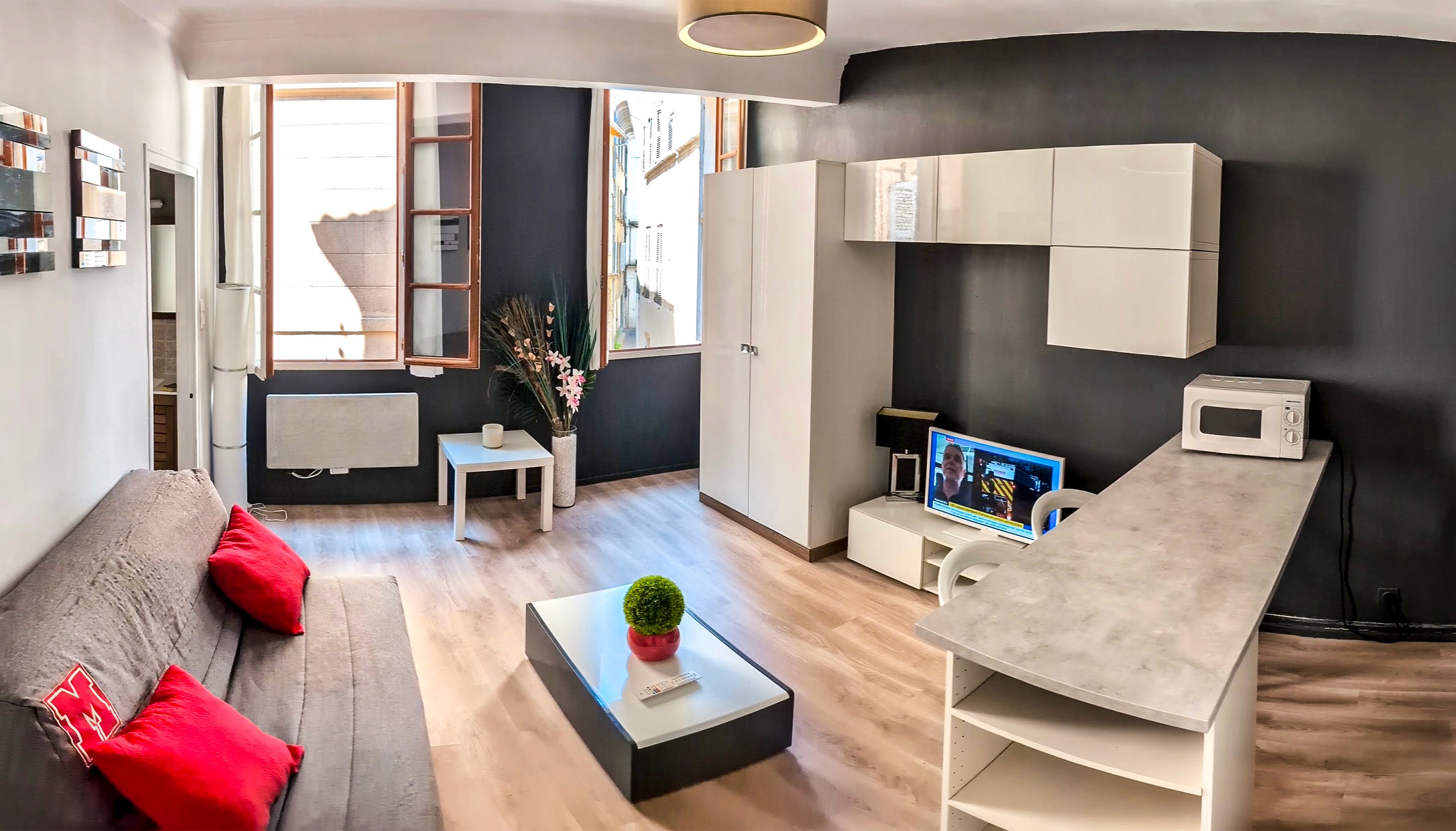 Modern loft interior with greenery, exposed brick walls, large glass windows, and vibrant yellow accents. Inviting atmosphere with natural light.