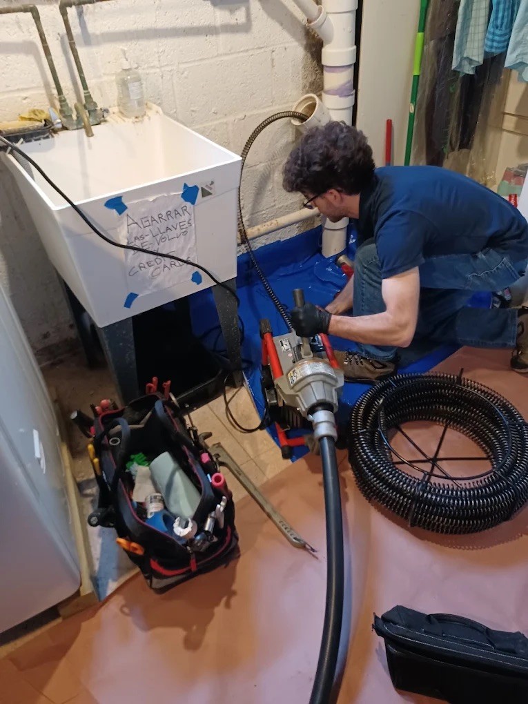 Spiro the plumber using a snake to clear out a clogged pipe