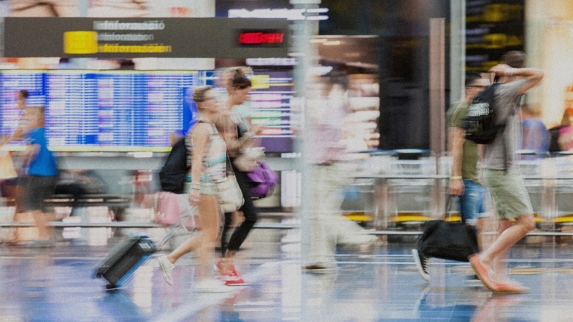 A grainy and motion blurred image of people walking through an airport.