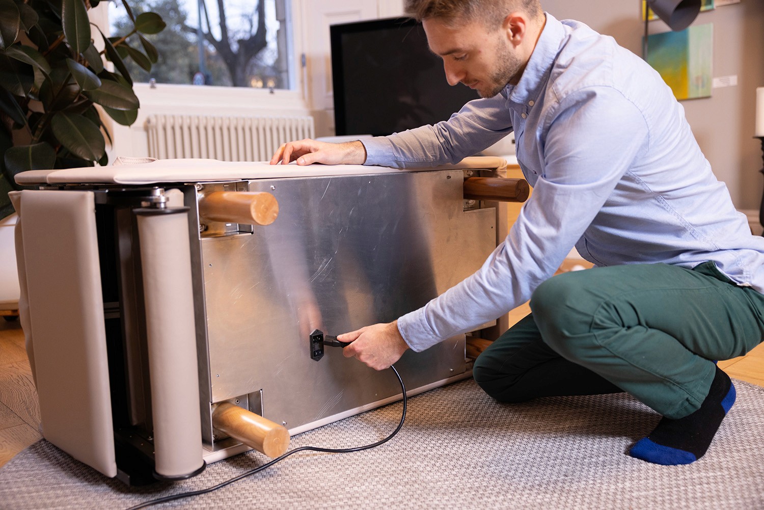 Person turning the BackHug device on its side to access the power socket underneath.