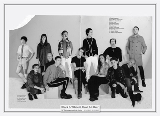 A teared folded black and white photo of a group of people, some siting on cubes and others standing.