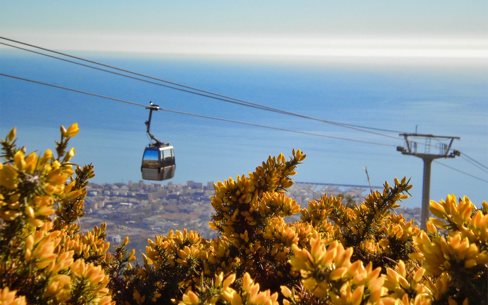 Teleférico sobre Benalmádena con vistas a la ciudad y al mar de fondo.