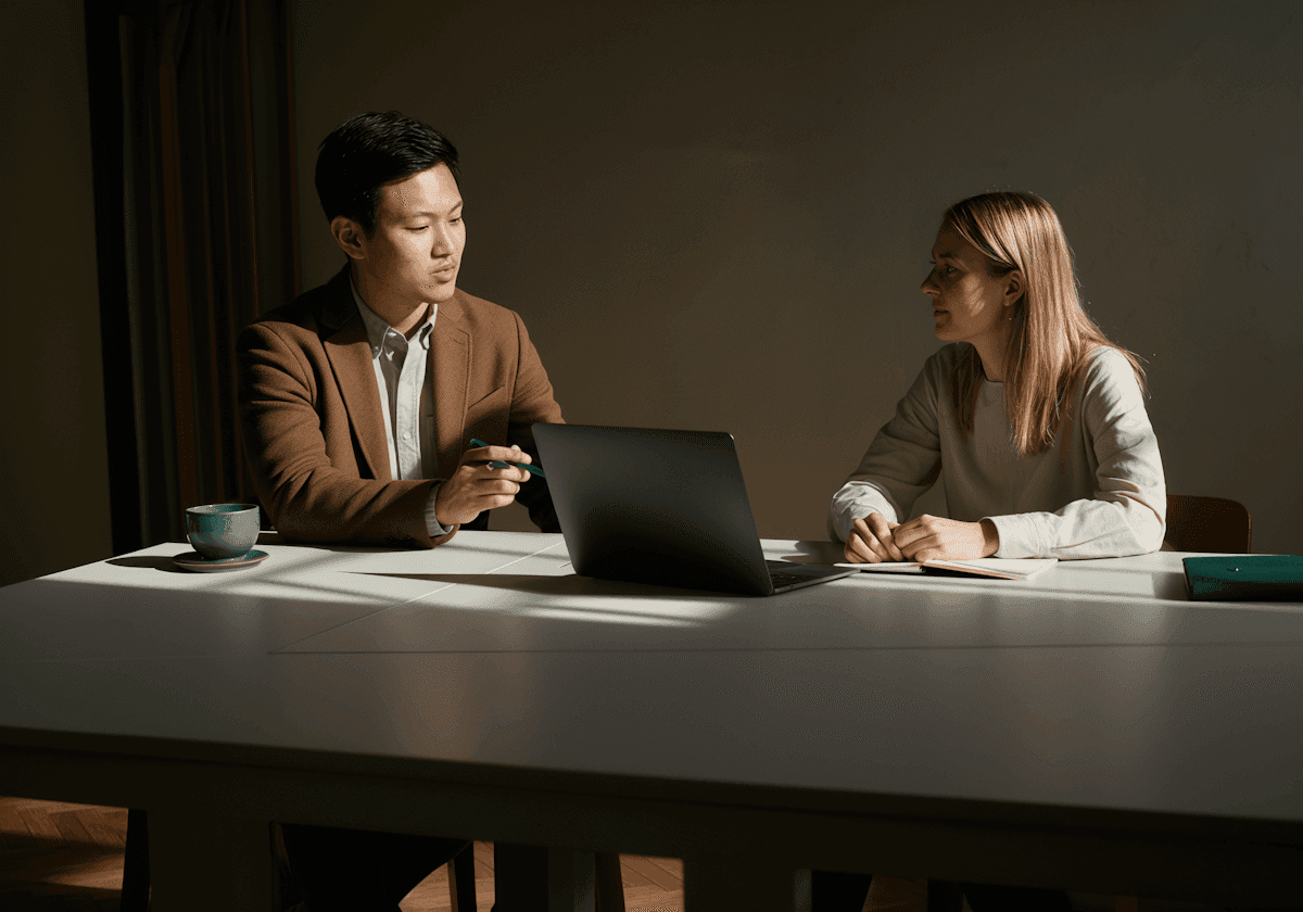 two people sitting in front of laptop