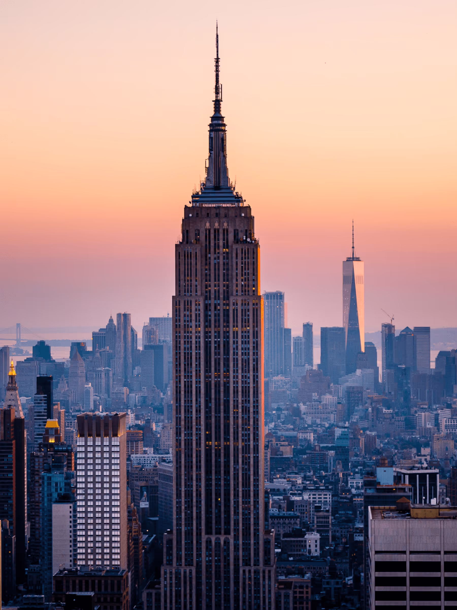Empire State Building at sunset with New York City skyline in background.