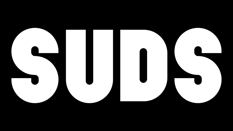A black background collage featuring the word "SUDS" in bold black letters, accompanied by pink, green, and white overlapping circles and a circular pattern listing "LAUNDRY | DRINKS | SOCIAL | POP UPS." Additional elements include a repeated "SUDS" design and a small pink circle.