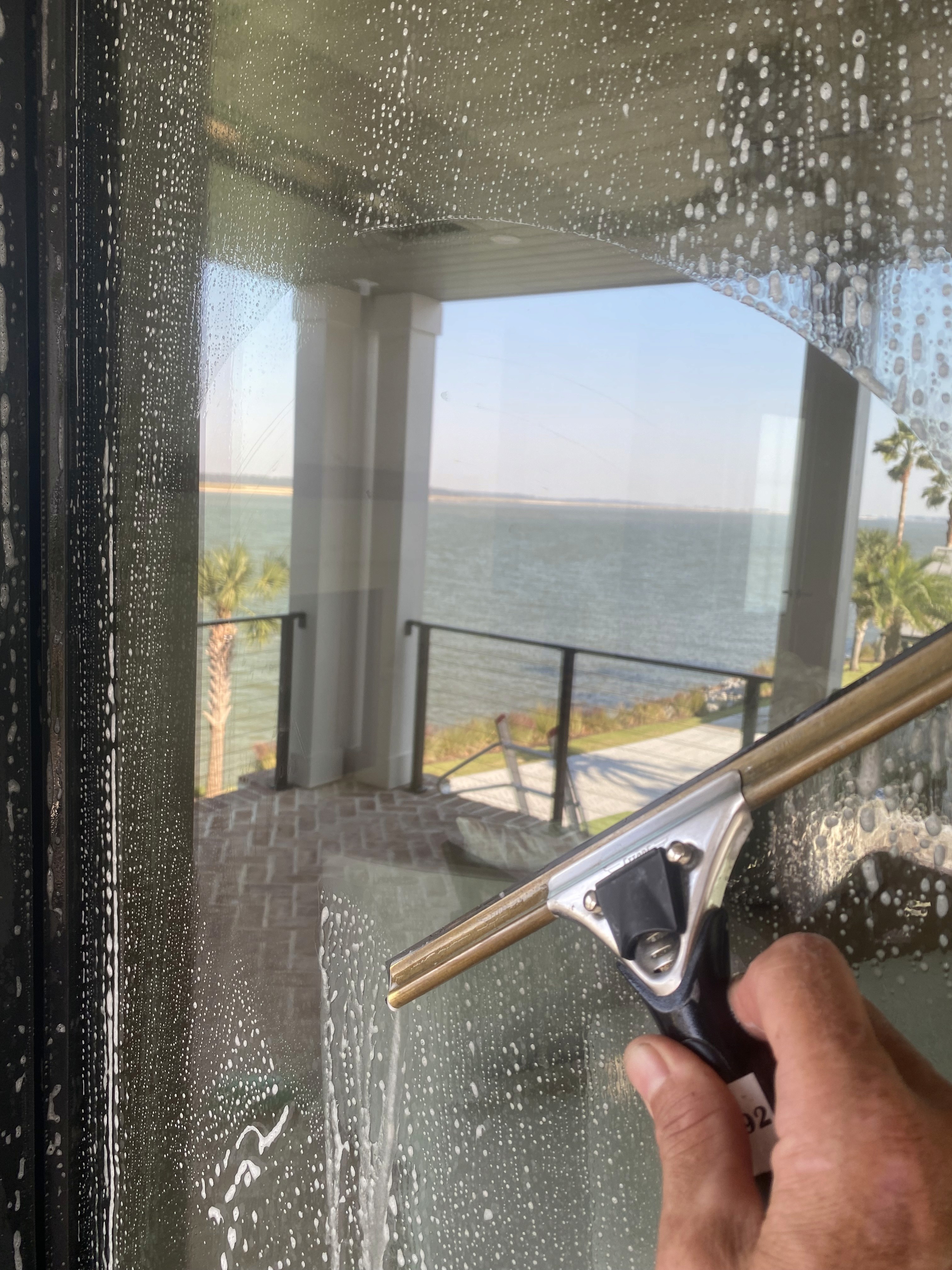Professional window cleaning pole and squeegee system being used for tall glass panels.