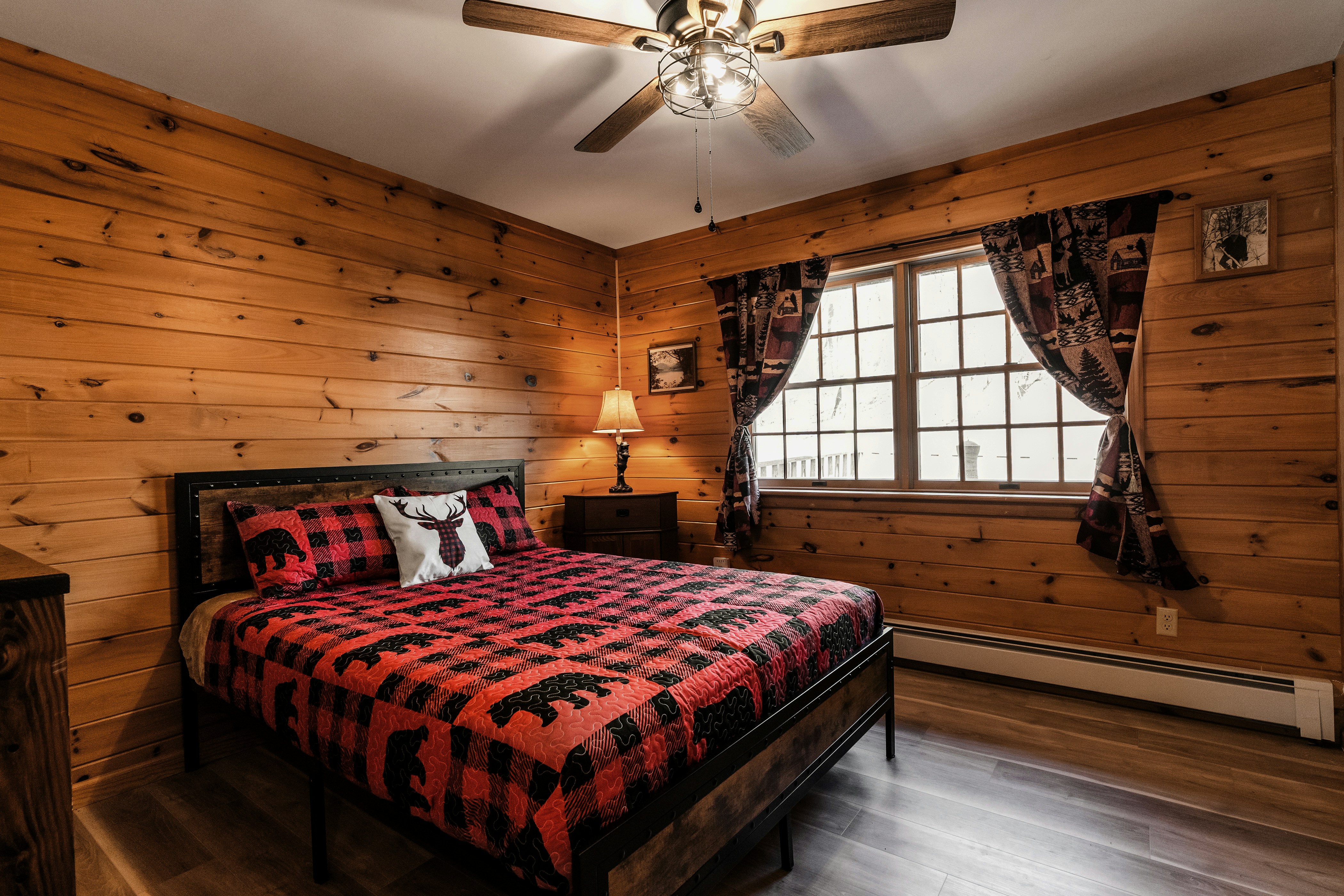 A cabin bedroom with a plaid quilt and pine walls