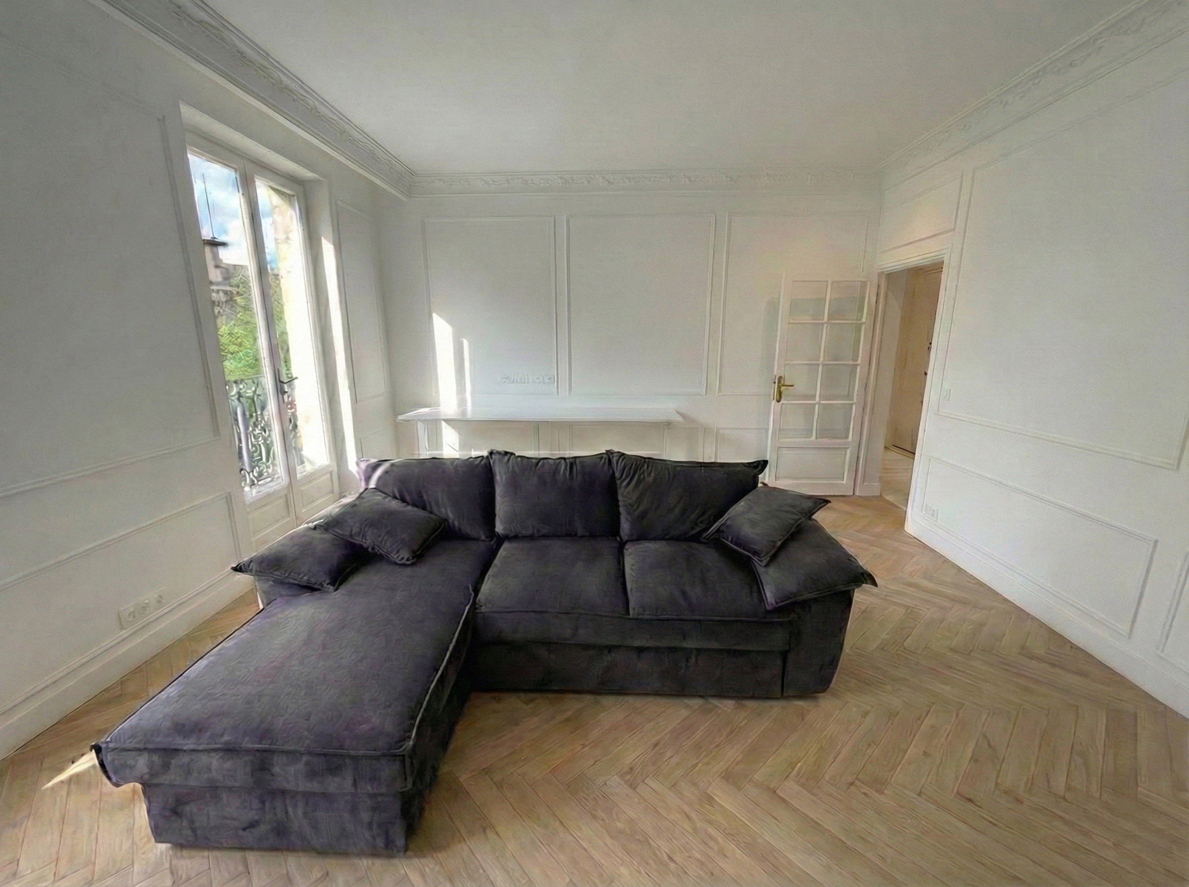 Espace de vie ouvert et lumineux avec moulures d'époque, grandes fenêtres et aménagement de salon contemporain.