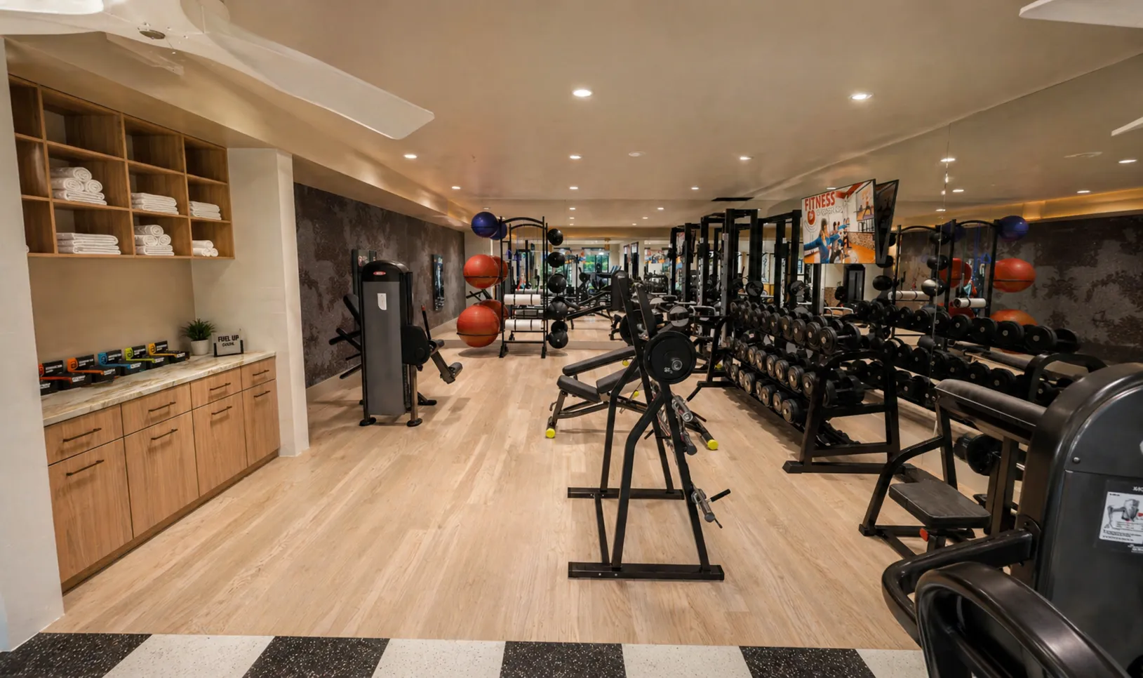 A gym room featuring various exercise equipment and a ceiling fan for ventilation.