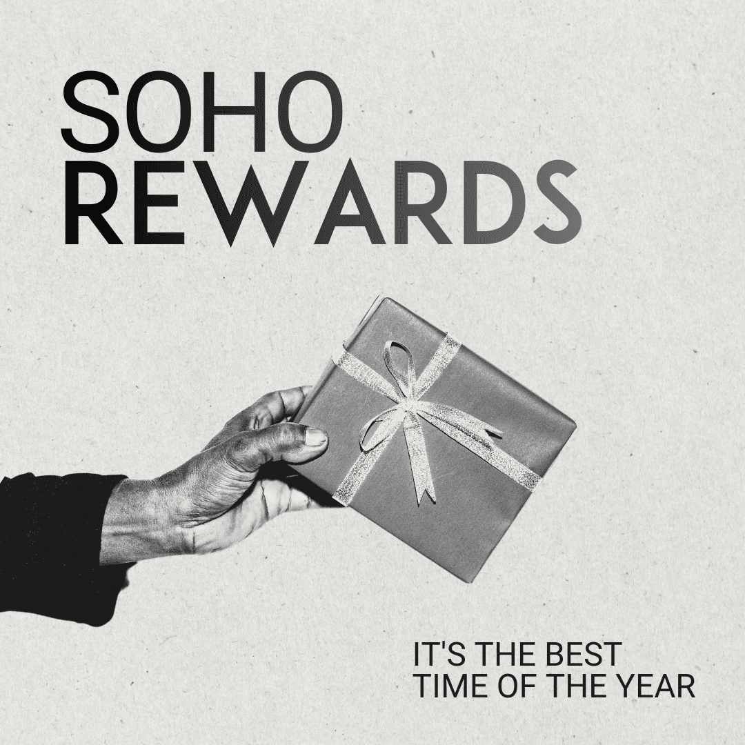 Three people in conversation with warm lighting, including a person wearing a hat and another person wrapped in what appears to be a textured shawl or sweater.