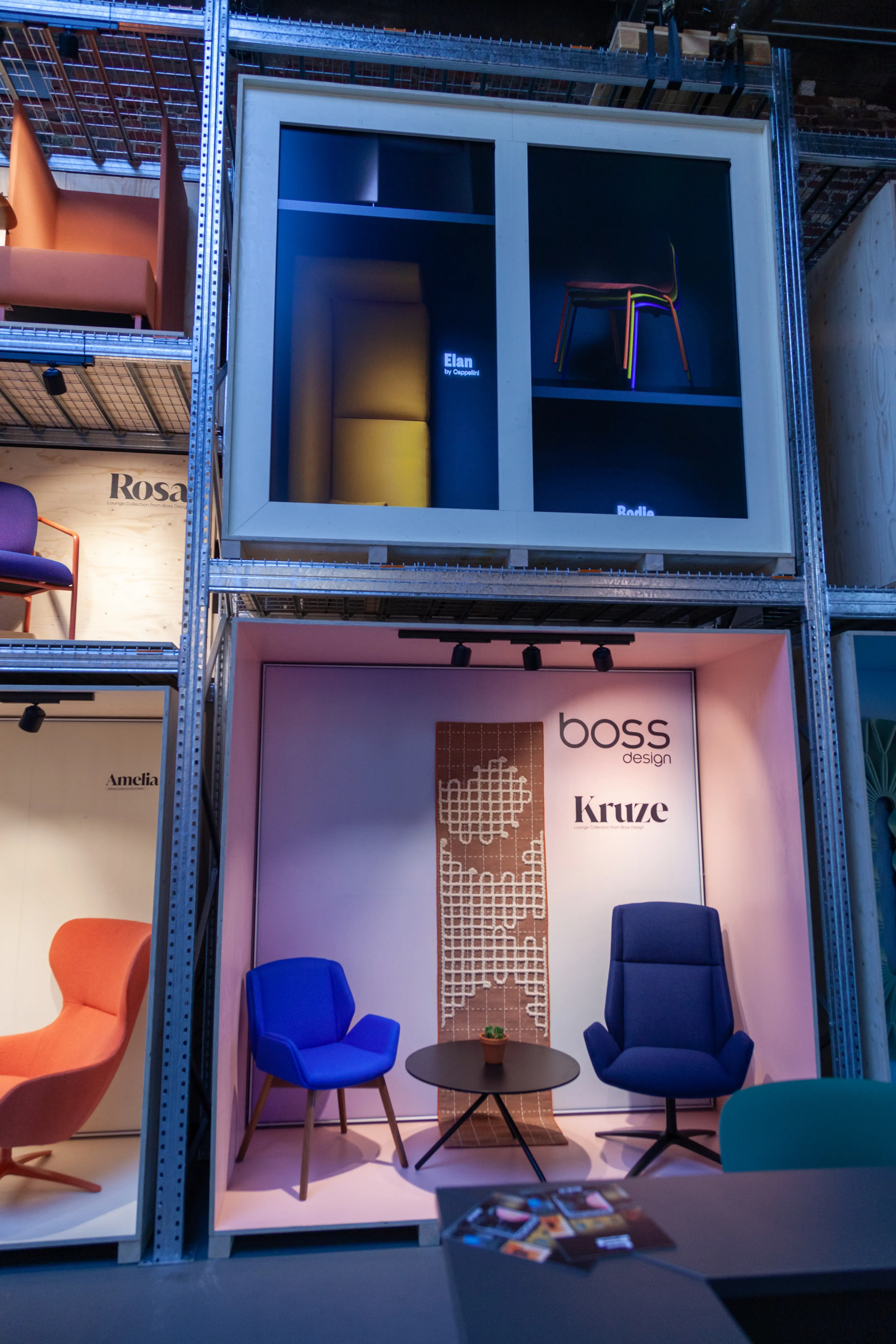 Display niche with blue Boss Design armchairs and a perforated wood panel within the steel rack at the Haworth ORGATEC booth.