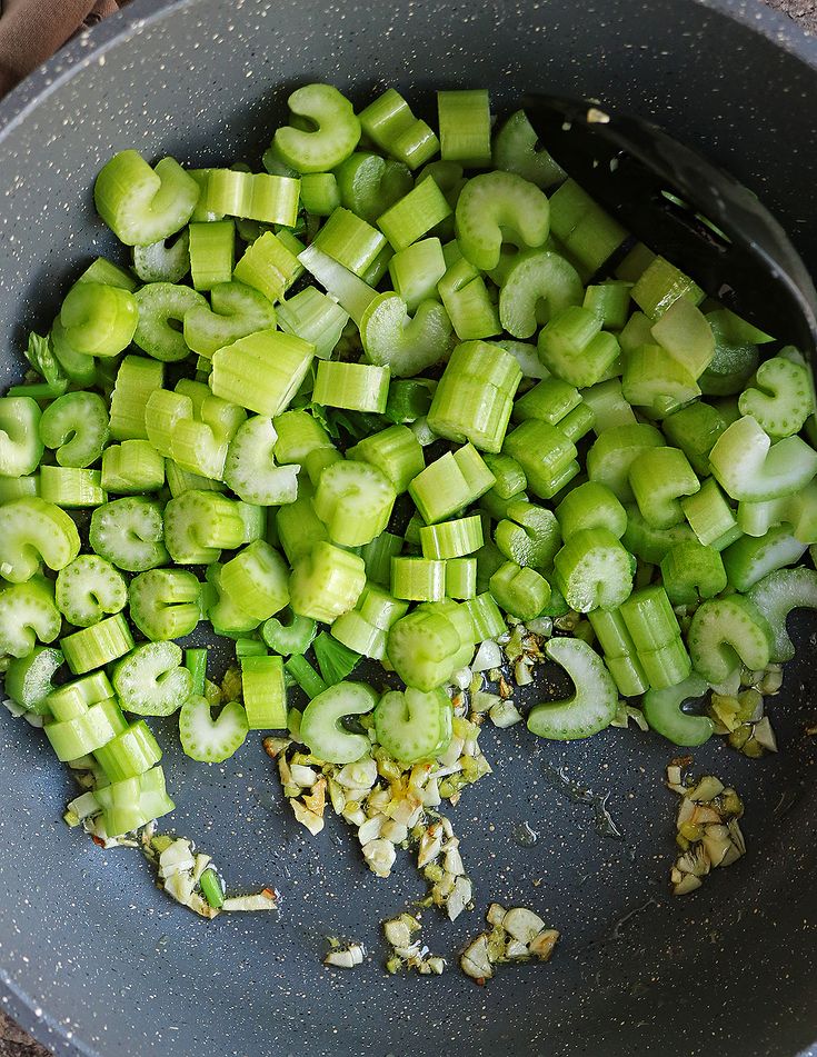Chopped celery sautéing in a non-stick pan with minced garlic, showing a simple and healthy cooking process